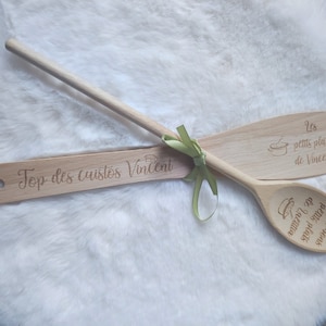 Op de afbeelding: Twee houten lepels met gegraveerde tekst. De bovenste lepel heeft de tekst "Top des cuistos Vincent". De onderste lepel heeft de tekst "Les bons petits plats de Laetitia" en "Les petits plats de Vincent".