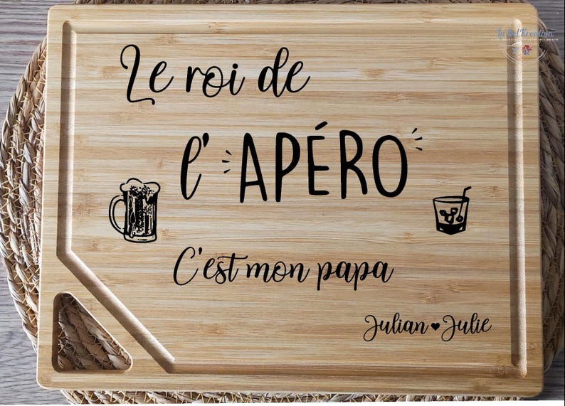 May include: A rectangular bamboo cutting board with the text "Le roi de l'AP&Eacute;RO C'est mon papa" and the names "Julian &hearts; Julie". The board features illustrations of a beer mug and a cocktail glass.