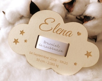Puede incluir: Una placa de madera clara con forma de nube grabada con el nombre Elena, un corazón pequeño y estrellas. Incluye una cinta blanca con la etiqueta Bracelet de naissance, la fecha 04 de septiembre de 2008, 10:20, 50 cm y 2,085 kg.