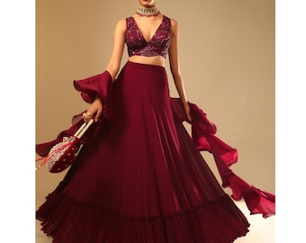 A Bollywood-style maroon lehenga with handwork leaf motifs and a ruffled dupatta would likely be glamorous and eye-catching, and traditional