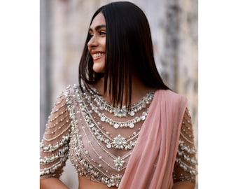 May include: A woman wearing a pink saree with a heavily embellished, beaded, and sequined blouse. The blouse features a layered design with silver coins and pearls.
