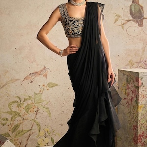 Diese Kombination aus einer schwarzen Netzbluse mit goldener Handarbeit und einem Sari mit Organza-Rüschen könnte ein schönes und klassisches Outfit ergeben.