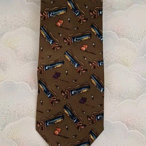 May include: A brown tie featuring a repeating pattern of golf bags, clubs, balls, and flags. The golf bags are blue and yellow, and the flags are purple and orange. The tie is made of a smooth fabric.