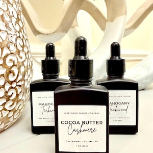 May include: Three dark brown bottles with black droppers, each with a white label. The center bottle reads "Cocoa Butter Cashmere" and the others read "Mahogany Teakwood". The bottles are wax warmers and diffuser oils, 1 oz (28g).
