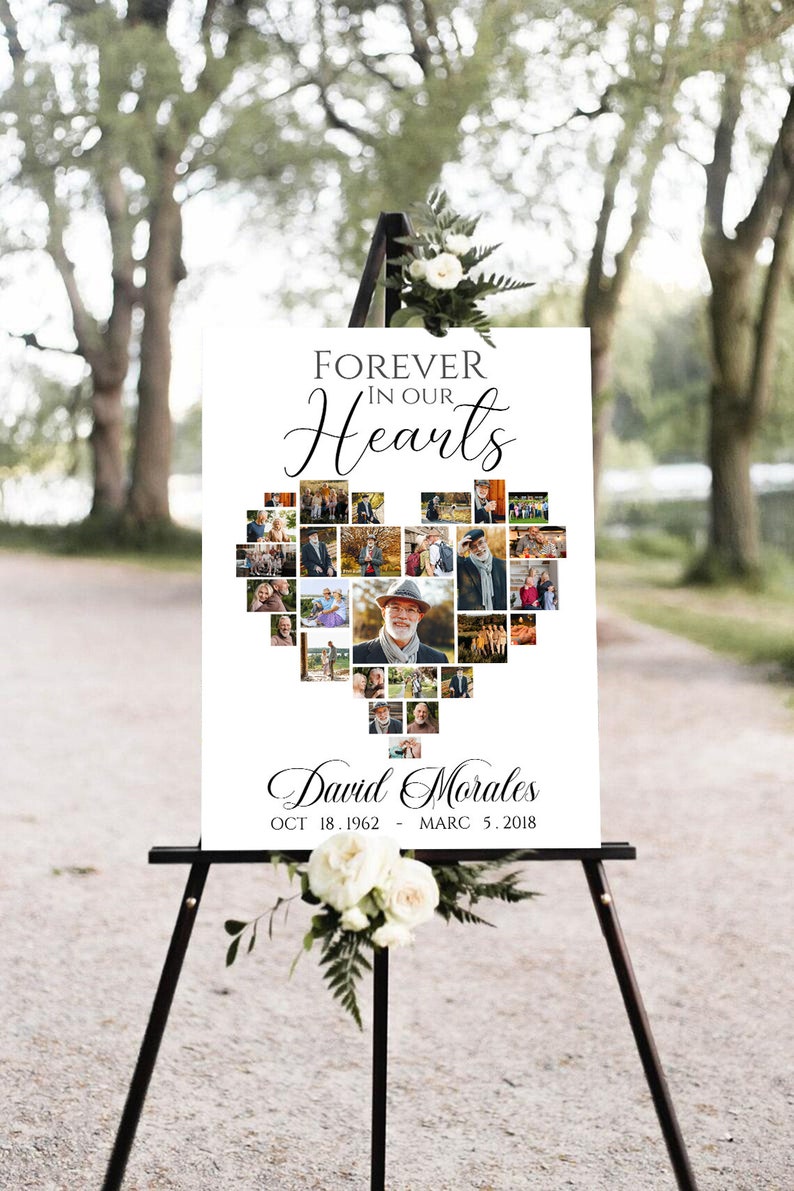 Pu&ograve; includere: Un cartello commemorativo su un cavalletto nero. Il cartello bianco presenta la scritta "Forever in our Hearts" sopra un collage di foto a forma di cuore. Sotto le foto c'&egrave; il nome "David Morales" e le date. Fiori bianchi e verde adornano il cavalletto.