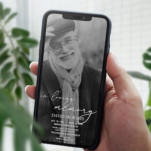 Op de afbeelding: Een zwart-witfoto van een man met een hoed en sjaal. De foto is te zien op een telefoonscherm met de tekst "in loving memory David Moraves Oct 18, 1943 - March 5, 2018 Service to be held at Local Church Address Sunday, April 1, 2018 at 1:00 PM Followed by a reception at Town Park Address, Maryland"