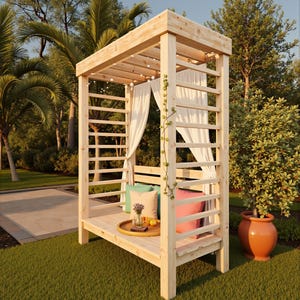 May include: A wooden outdoor gazebo with a slatted roof and sides, draped with white curtains. The gazebo has a built-in bench with colorful pillows and a tray with a vase and fruit. String lights are strung across the top. The gazebo is set on a green lawn.