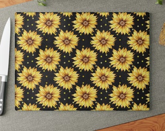 Peut inclure: Une planche à découper noire avec un motif répétitif de tournesols jaunes et de petits points jaunes.