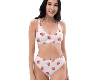 May include: A white bikini with a strawberry print. The top has a scoop neck and adjustable straps. The bottoms are high-waisted and have a cheeky cut.