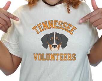 May include: White t-shirt with an orange graphic of a dog and the text "Tennessee Volunteers".