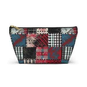 Op de afbeelding: Een zwart-witte patchwork-design toilettas met rode, blauwe en witte accenten. De tas heeft een ritssluiting.