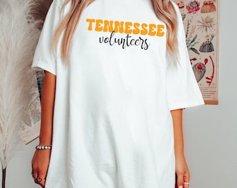 Può includere: Maglietta bianca oversize con il testo "Tennessee Volunteers" in lettere arancioni.