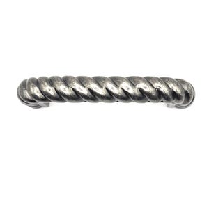 Può includere: Una maniglia per mobili in metallo argentato e attorcigliato. La maniglia ha un design a forma di corda ed è lunga circa 15 cm. L'hardware ha una finitura anticata ed è posto su uno sfondo bianco.