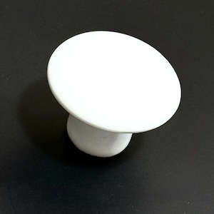 Może przedstawiać: Biały ceramiczny gałka w kształcie grzyba z gładkim, zaokrąglonym wierzchołkiem i lekko fakturowaną podstawą.