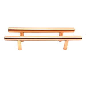 May include: Two copper-coloured cabinet pulls with a modern, minimalist design. Each pull features a horizontal bar supported by two vertical posts. The pulls are made of a shiny, metallic material.