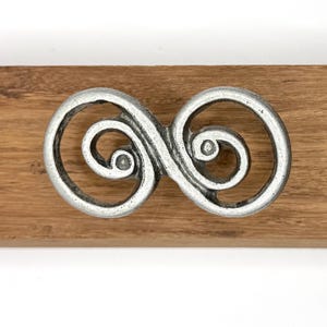 Tirador de doble espiral con diseño caprichoso en peltre antiguo. Aproximadamente 6,35 cm de largo, 3,2 cm de diámetro central.