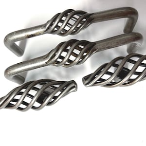 May include: Four silver metal cabinet door pulls with a twisted wire design. The pulls are in various positions on a white background.