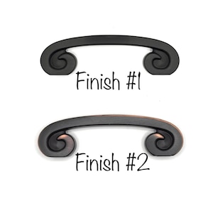 May include: Two decorative cabinet pulls with a curved design and scroll ends. The top pull is black, and the bottom pull is bronze. The text "Finish #1" and "Finish #2" are below each pull.