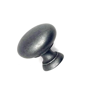 May include: Oval-shaped, antique-style cabinet knob in a dark, muted gray finish. The knob has a textured surface and a classic design, suitable for drawers or cabinet doors. The base is a smaller, rounded shape.