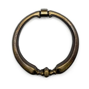 May include: A circular, antique brass ring pull with a smooth, rounded finish. The ring is designed to be used as a handle for doors, cabinets, or drawers.