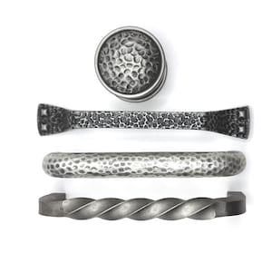 Tiradores y pomos de metal retorcido con efecto martillado y acabado peltre con textura rústica de granja.