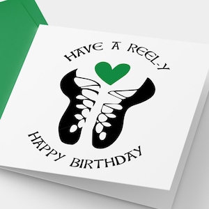 Puede incluir: Tarjeta de cumpleaños blanca con un corazón verde e ilustración negra de zapatos de baile irlandeses. La tarjeta dice "Have a reel-y Happy Birthday" y va acompañada de un sobre verde.