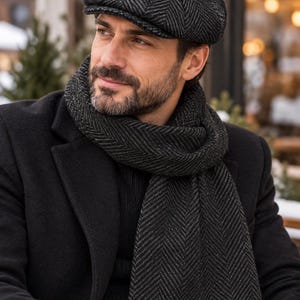 May include: A dark gray and black herringbone patterned flat cap and a matching long scarf. The cap features a structured crown and a short brim, while the scarf is wrapped around the neck, both made from a textured wool-like fabric.