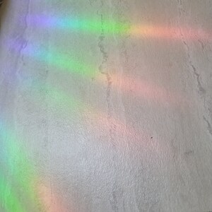 Puede incluir: Una superficie blanca texturizada con m&uacute;ltiples reflejos de luz arco&iacute;ris.