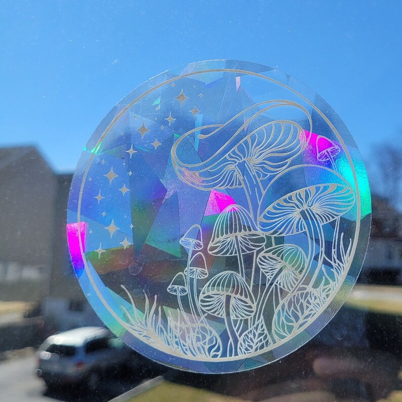 Puede incluir: Una pegatina hologr&aacute;fica con un dise&ntilde;o de setas blancas sobre un fondo azul con estrellas blancas. La pegatina es redonda y tiene un acabado iridiscente.