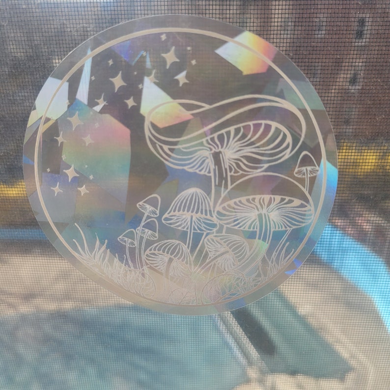 Puede incluir: Una pegatina hologr&aacute;fica con un dise&ntilde;o de setas blancas y estrellas sobre un fondo oscuro.