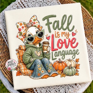 May include: A white canvas print featuring a cartoon duck wearing a floral bow, green sunglasses, and a green hoodie, sitting on a plaid chair. The text reads Fall is my Love Language. Three pumpkins in orange, white, and green sit below the duck.