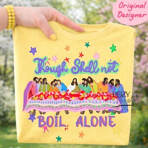 May include: Yellow crewneck sweatshirt with a colorful graphic. The design features the text "Though Shell not Boil Alone" above a depiction of people at a table. The design includes stars and a decorative border.