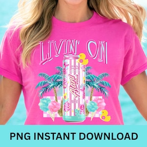 May include: A bright pink t-shirt with the words "LIVIN ON" in a light blue font. The shirt features a graphic of a cotton candy-flavored energy drink can, palm trees, cotton candy, and rubber ducks. The words "Alani Energy" are visible on the can.