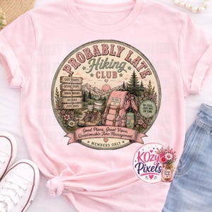 May include: A light pink t-shirt featuring a circular graphic with the text "Probably Late Hiking Club." The design includes a wooden signpost, hiking boots, a backpack, mountains, and trees, with the phrase "Good Plans, Great Views, Questionable Time Management" printed on a banner at the bottom.