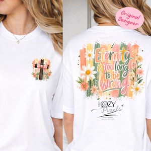 May include: White t-shirt featuring a cross with a pink bow and floral accents on the front. The back of the shirt displays the text "Eternity is too long to be Wrong" with floral and brushstroke designs. The shirt is from "KOZY Pixels".