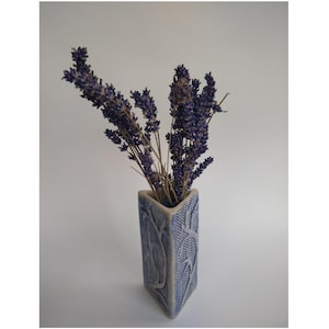 May include: A triangular ceramic vase with a blue and white glaze and a textured design. The vase is filled with dried lavender flowers.