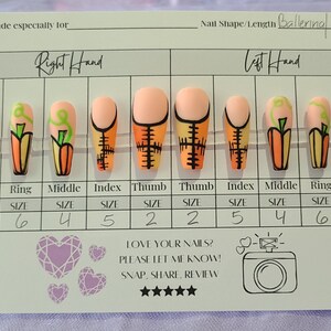May include: A white card with a size chart for fake nails. The nails are decorated with a pumpkin design and the card says "Right Hand" and "Left Hand". The card also says "Nail Shape/Length Ballerina Long".
