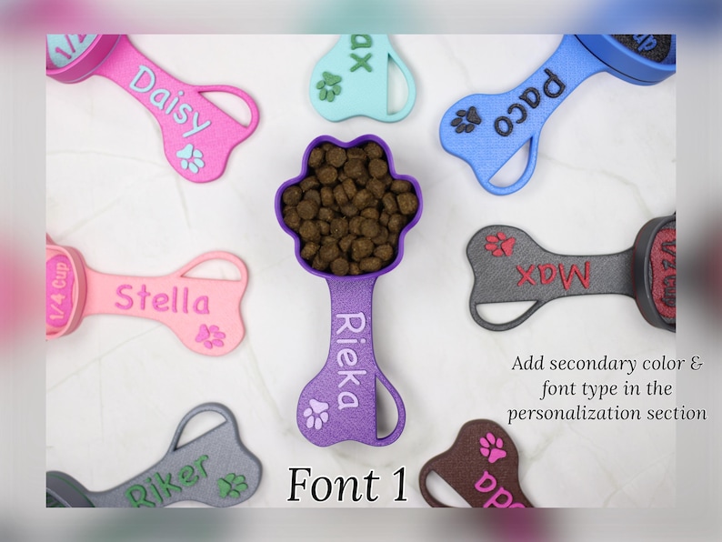 K&ouml;nnte beinhalten: Eine Sammlung bunter, knochenf&ouml;rmiger Hundefutterl&ouml;ffel mit Pfotenabdr&uuml;cken und personalisierten Namen, darunter Daisy, Stella, Rieka, Paco, Riker, Max und da. Die L&ouml;ffel sind aus Kunststoff und haben an einem Ende einen Messbecher. Der Text "Font 1" wird unter den L&ouml;ffeln angezeigt.