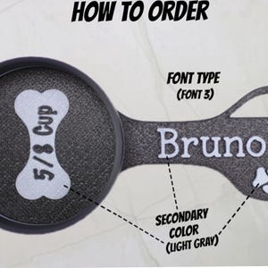 May include: A black and light gray pet food scoop with the text "5/8 Cup" and the name "Bruno". The scoop is shaped like a bone and includes a paw print design. The text "HOW TO ORDER" is at the top.