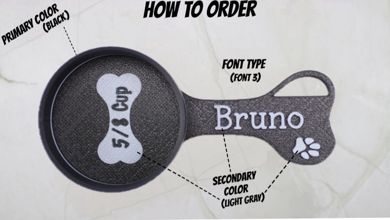 May include: A black and light gray pet food scoop with the text "5/8 Cup" and the name "Bruno". The scoop is shaped like a bone and includes a paw print design. The text "HOW TO ORDER" is at the top.