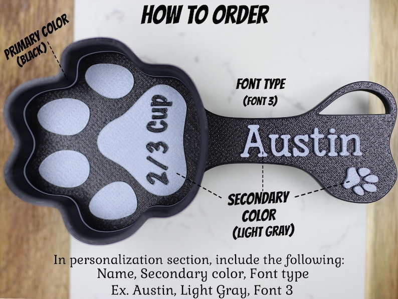 K&ouml;nnte beinhalten: Ein schwarzer und hellgrauer Messbecher in Form einer Pfote mit einem Fassungsverm&ouml;gen von 2/3 Tasse. Der Becher hat einen Griff mit dem Namen "Austin" in wei&szlig;. Der Text "FONT TYPE (FONT 3)" ist &uuml;ber dem Namen sichtbar. Der Text "PRIMARY COLOR (BLACK)" ist &uuml;ber dem Becher sichtbar. Der Text "SECONDARY COLOR (LIGHT GRAY)" ist unter dem Griff sichtbar. Der Text "HOW TO ORDER" ist oben im Bild sichtbar.