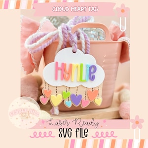 May include: A cloud-shaped tag with the name "HYNLE" in rainbow colors, hanging below colorful heart shapes. The tag is part of a design labeled "Laser Ready SVG File" and is set against a pink background with a pink bucket.