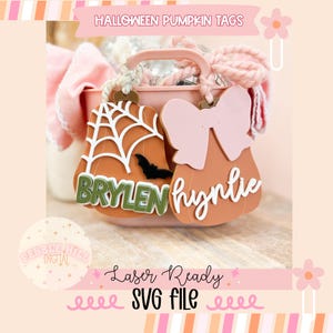 May include: Two pumpkin-shaped Halloween tags. One features a white spiderweb design and a black bat, with the name "BRYLEN" in green. The other has a pink bow and the name "hynlie" in white. The tags are laser-ready SVG files.