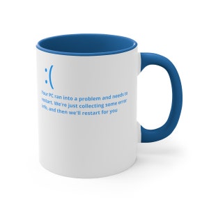 May include: White coffee mug with a blue rim and handle. The mug has a blue text that reads: "( :( ) Your PC ran into a problem and needs to restart. We're just collecting some error info, and then we'll restart for you"