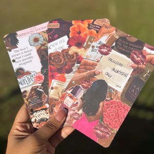 May include: Three decorative cards are held in a hand, each featuring collaged images and text. The cards display floral and beauty-related imagery, such as roses, lipstick, and perfume bottles. Text includes "Princess Treatment Only!" and "Black Women are the purest form of a..."