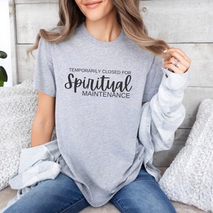 May include: A gray t-shirt with the text "Temporarily Closed for Spiritual Maintenance" in black.