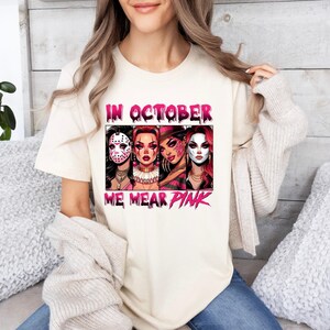 K&ouml;nnte beinhalten: Ein wei&szlig;es T-Shirt mit einem pinkfarbenen Grafikdesign, das vier Frauen mit Halloween-Make-up und dem Text "In October We Wear Pink" zeigt.