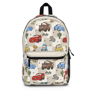 Puede incluir: Una mochila beige con un patrón a cuadros con coches de dibujos animados, cactus y banderas de carreras. Los coches son rojos, azules, marrones y amarillos. La mochila tiene una cremallera negra y un asa negra.