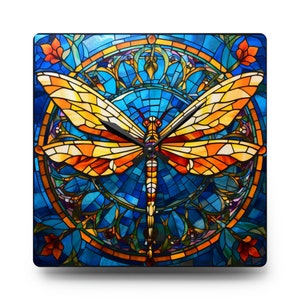 May include: A stained glass clock featuring a dragonfly with orange and yellow wings against a blue background. The clock face is a circular design with a stained glass pattern.