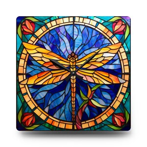May include: A square clock with a stained glass design featuring a dragonfly with orange and yellow wings against a blue background. The clock face is surrounded by a border of stained glass flowers and leaves.